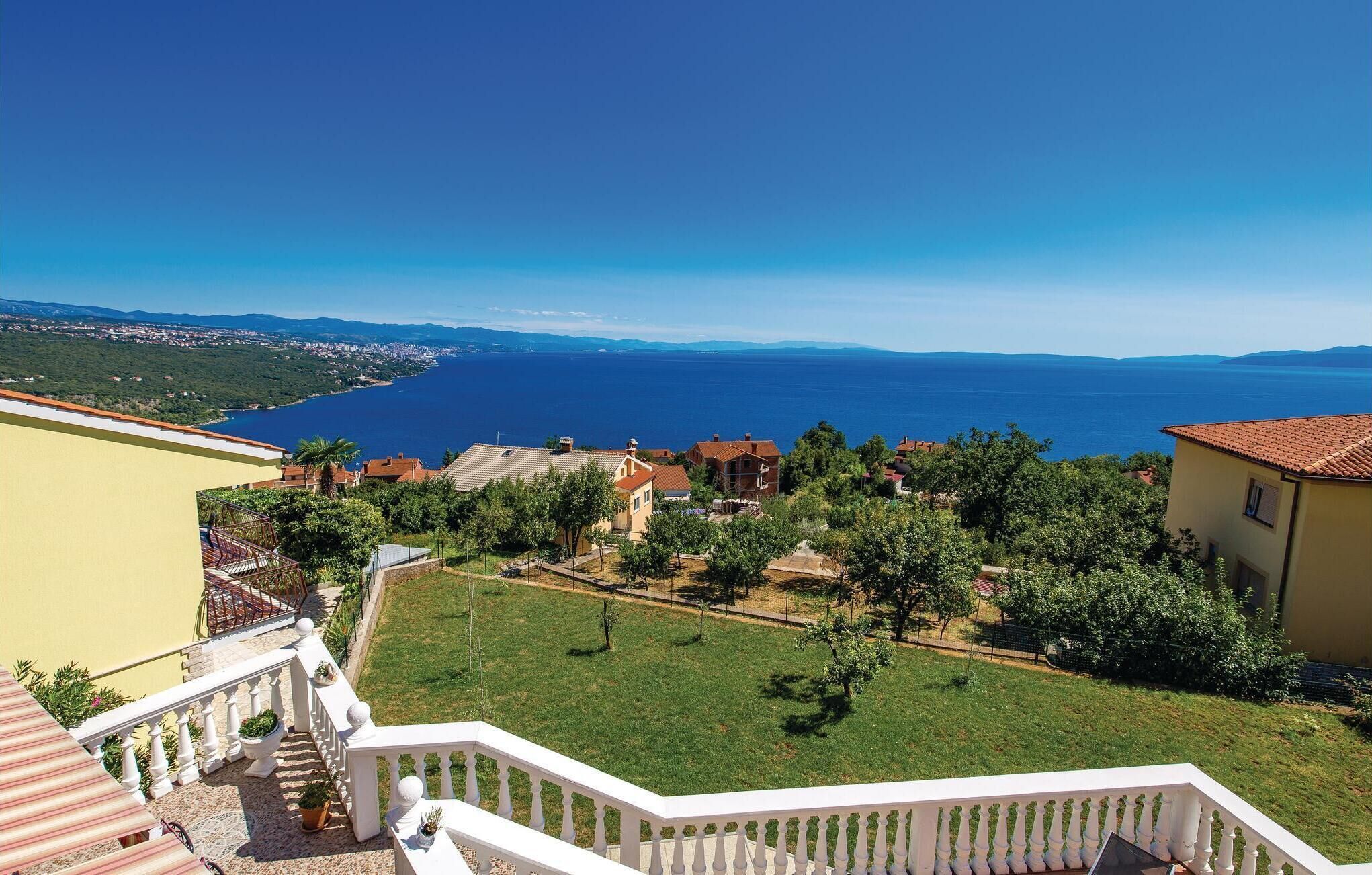 A residential area with a view of the sea, a staircase, and a well-maintained lawn.
