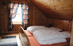 A wooden cabin bedroom with a single bed, a window with colorful curtains, and a wooden ceiling. - Stunning home in Evanger with kitchen (Evanger)