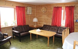 A cozy cabin interior with a wooden interior, two leather sofas, a wooden table, and red curtains. - Stunning home in Evanger with kitchen (Evanger)