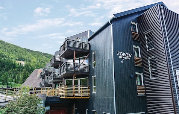 En byggnad med flera våningar, mörk fasad, balkonger och en skylt med texten ”STAVEN LEILICHTER”.