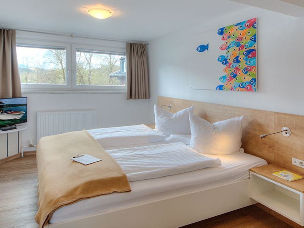 Ein Hotelzimmer mit zwei Betten, einem Fernseher, einem Fenster mit Vorhängen und farbigem Fisch-Wandbild.