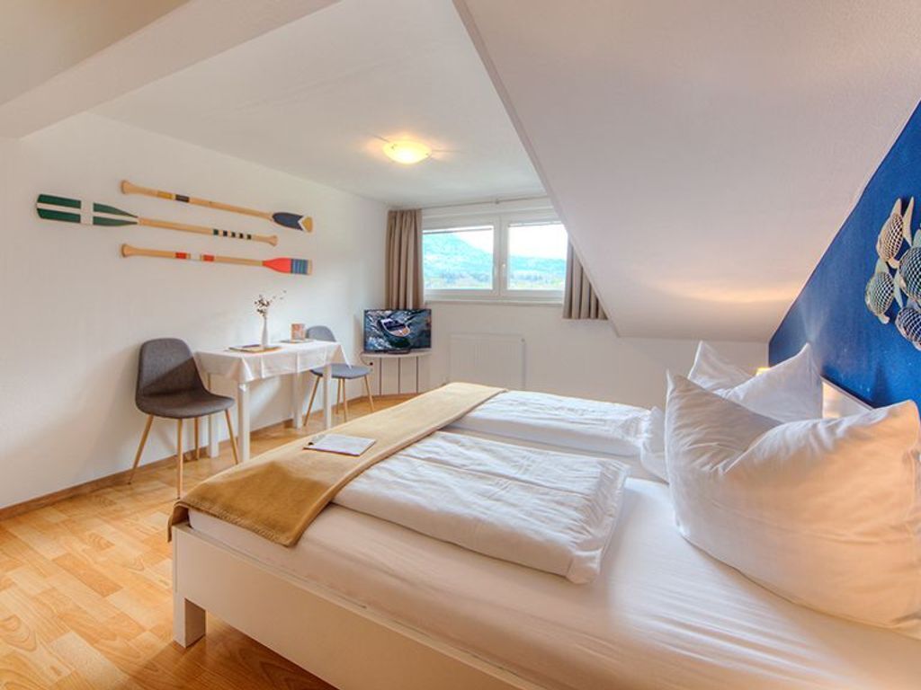 Une chambre d’hôtel avec un lit, un bureau, une chaise, une télévision et une fenêtre.