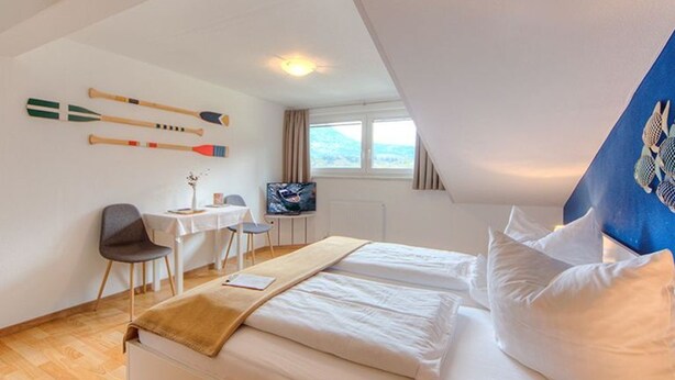 Ein Hotelzimmer mit Bett, Schreibtisch, Stuhl, Fernseher und Fenster.
