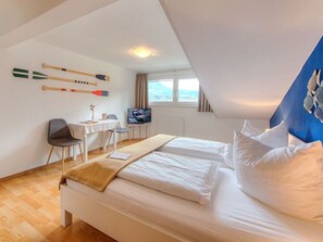 Habitación de hotel con cama, escritorio, silla, televisión y ventana.