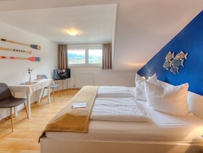 Een hotelkamer met een bed, een bureau, een stoel en een raam met gordijnen.