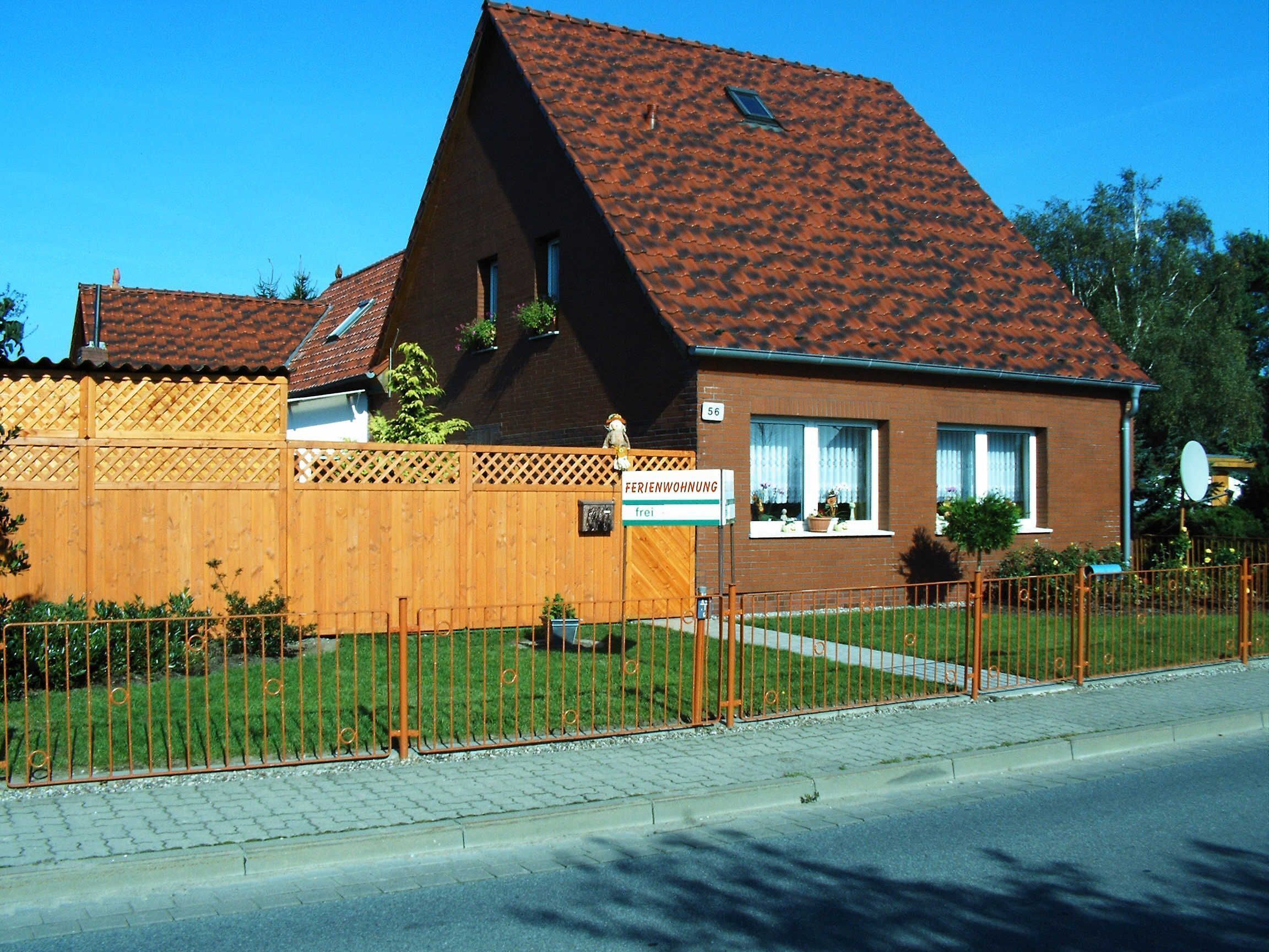 Ein zweistöckiges Haus mit einem geneigten Dach, einem Holzzaun und einem Schild, das anzeigt, dass es sich um eine kostenlose Herberge handelt.