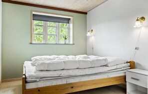 A bedroom with a wooden bed, a window with a view of greenery, and a bedside table with a lamp. - Lovely home in Augustenborg with WiFi (Augustenborg)