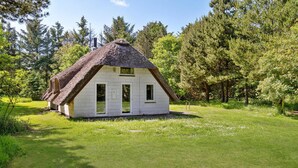A small, white, thatched-roof house surrounded by lush greenery and trees. - Lovely home in Ulfborg with WiFi (Ulfborg)