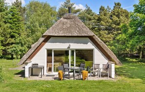 A thatched-roof cottage with a sliding glass door, outdoor seating, and a chimney. - Lovely home in Ulfborg with WiFi (Ulfborg)