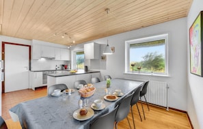 Une cuisine moderne avec des meubles blancs, un îlot central et un coin repas où la table est mise pour le petit-déjeuner.