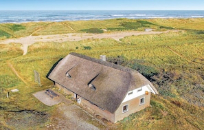 A house with a sloped roof, a brick exterior, and a small window. There is a paved path leading to the house and a picnic table nearby. - Awesome home in Ringkøbing with sauna (Ringkøbing)