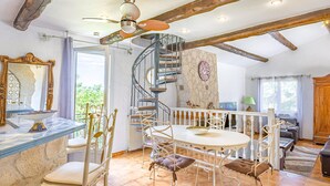 A spacious dining area with a round table and chairs, a spiral staircase, and a rustic ceiling. - Pet friendly home in Roujan (Roujan)