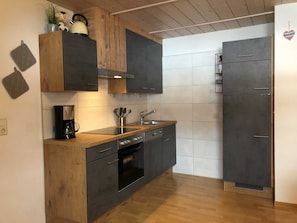 Une cuisine moderne avec des meubles de couleur sombre, un plan de travail en bois, une machine à café et un évier.