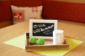 A table with a tray holding a mug and a sign with text, a cushion with a reindeer design, and a wooden table. - Double room Berggeflüster - Haus Lorenz (Grän)