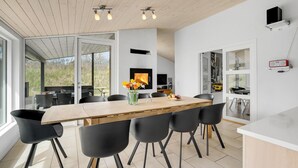 A modern dining area with a wooden table, black chairs, and a vase of flowers. - Beautiful home in ålbæk with WiFi (Ålbæk)
