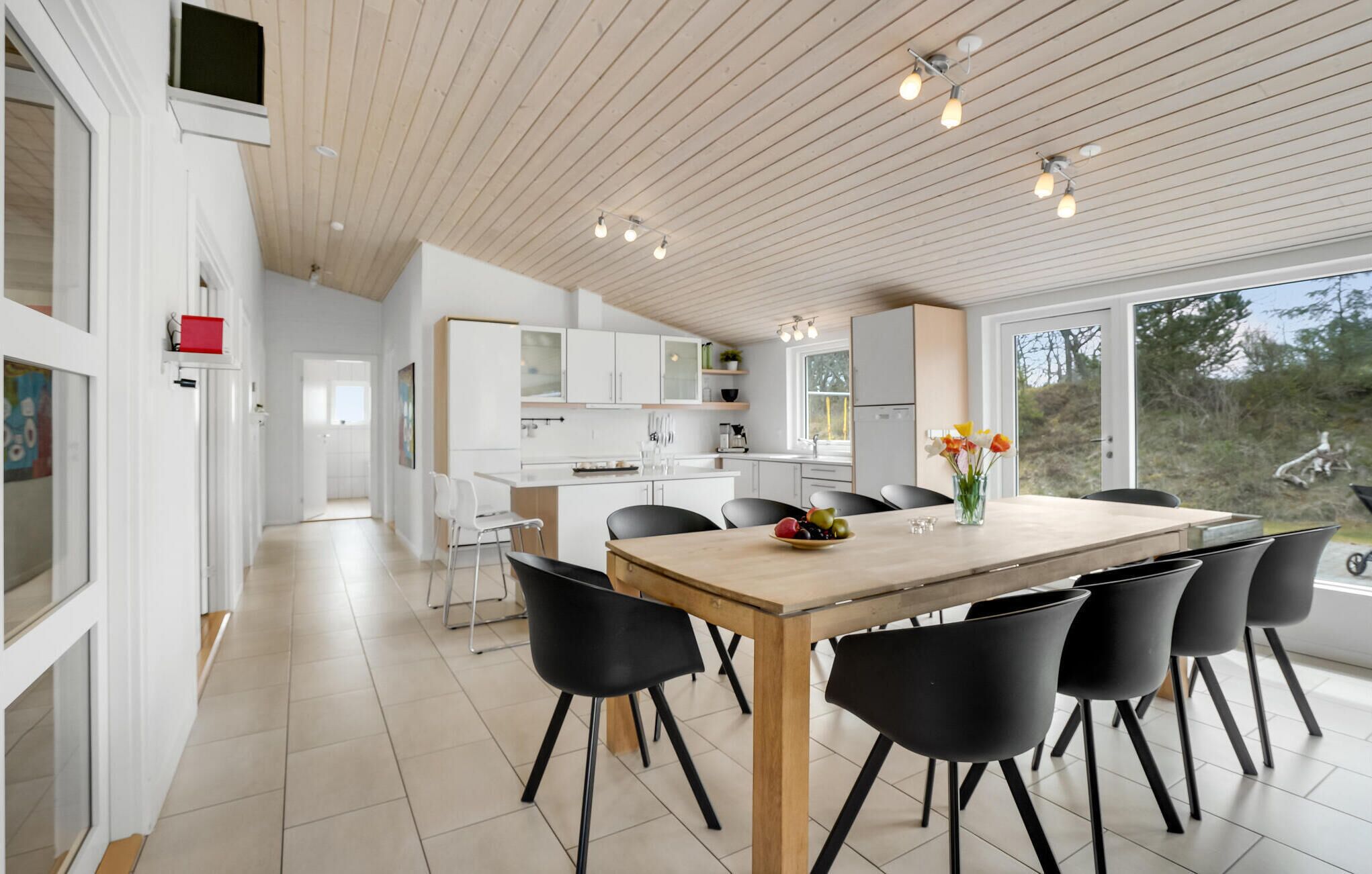 A modern kitchen with white cabinets, a wooden dining table, and black chairs.