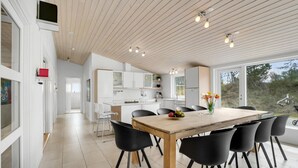 A modern kitchen with white cabinets, a wooden dining table, and black chairs. - Beautiful home in ålbæk with WiFi (Ålbæk)