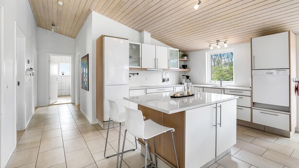 A modern kitchen with white cabinets, a central island, and a wooden ceiling. - Beautiful home in ålbæk with WiFi (Ålbæk)