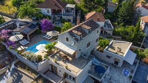 Une maison à plusieurs étages dotée d’une piscine, d’un espace salon extérieur et d’un jardin.