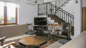 Een woonkamer met een bank, een houten salontafel, een televisie en een trap.
