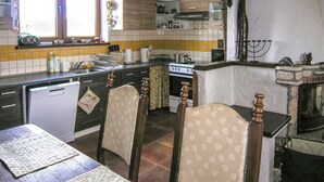 Een keuken met een fornuis, wastafel en een eethoek met stoelen.