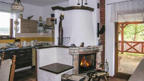 Een keuken met een stenen openhaard, houten keukenkastjes en een hanglamp.