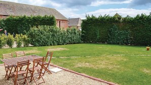 A patio with a wooden table and chairs, surrounded by a gravel area and a grassy lawn. - 2 bedroom lovely home in Trie-Château (Trie-Château)