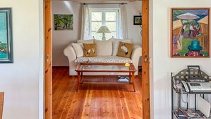 Ein Wohnzimmer mit Holzboden, einer Couch, einem Couchtisch und einem Gemälde an der Wand.