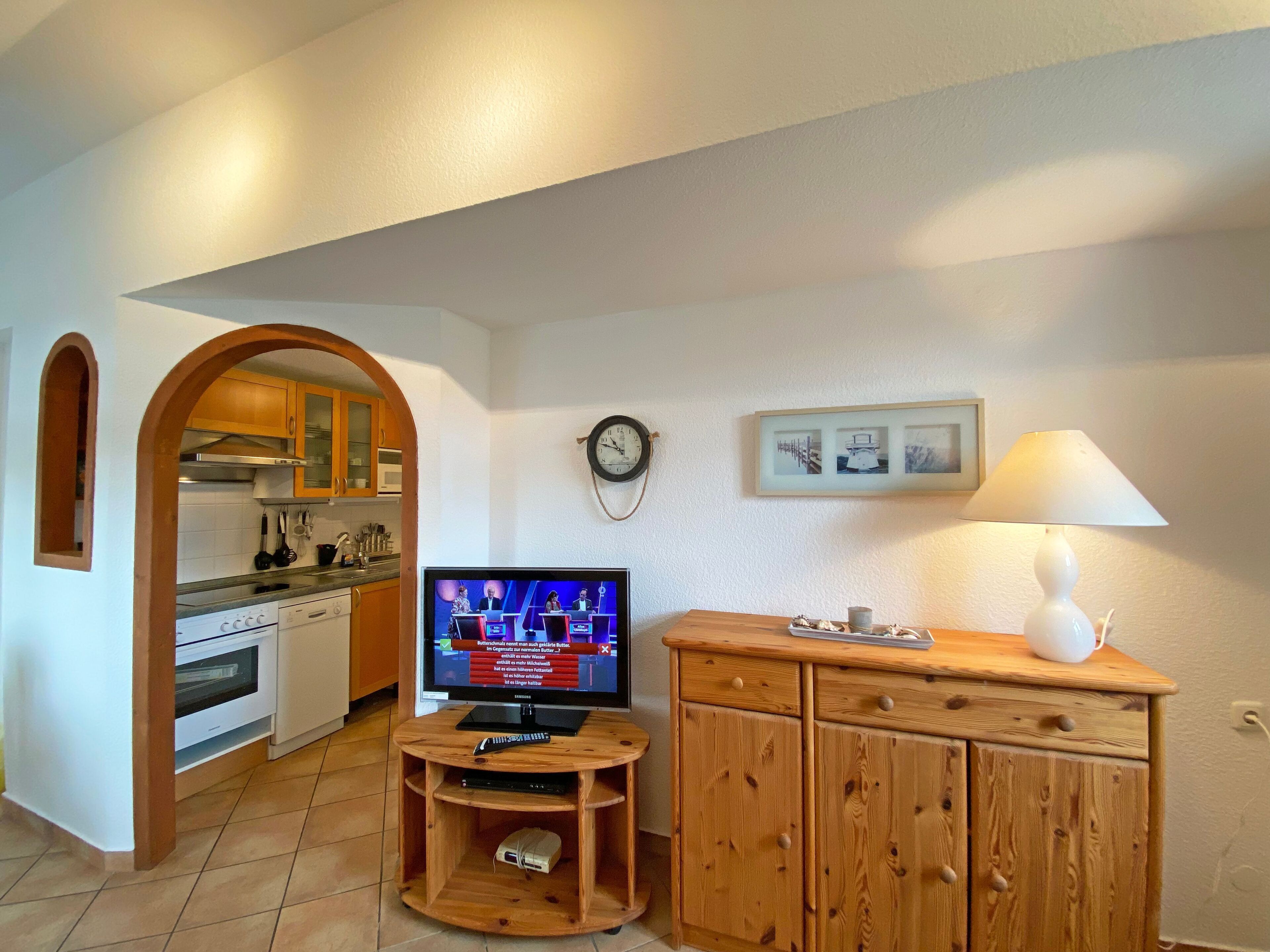 A compact living space with a kitchen, a television, and a wooden cabinet.