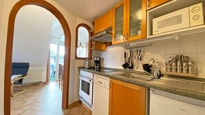 Una cocina con armarios de madera, microondas, cafetera y lavavajillas.