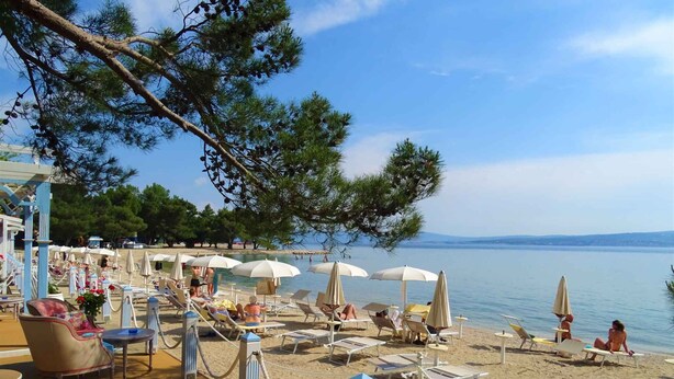 Un espace aménagé au bord de la plage, avec des chaises longues, des parasols et une zone dédiée à la piscine.