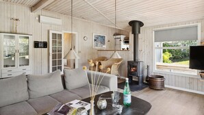 Ein gemütliches Wohnzimmer mit einer Couch, einem Couchtisch mit Zeitschriften, einem Kamin und einem Fernseher.