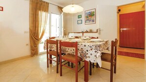 A dining area with a table set for four, wooden chairs, a ceiling light, and a door with a red frame. - Gorgeous home in Jadranovo (Jadranovo)