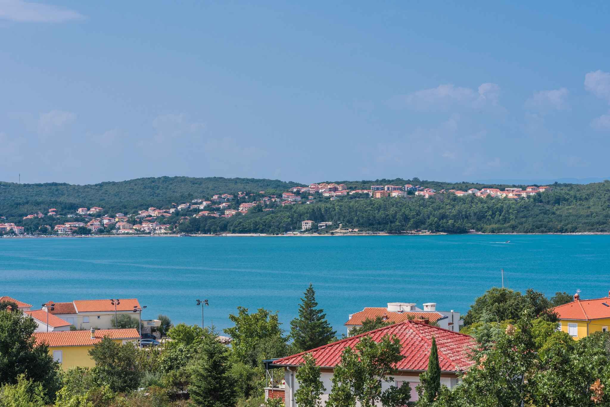 A coastal town with buildings on a hillside overlooking a large body of water.