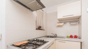 Eine moderne Küche mit Gasherd, Spüle und weißen Schränken.
