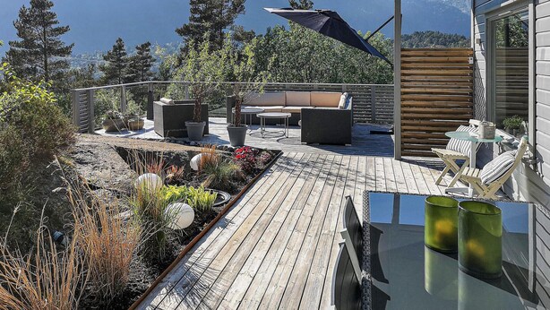 A wooden deck with outdoor furniture, potted plants, and a view of mountains. - Awesome home in Hebnes with house sea view (Hebnes)