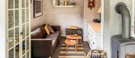 A cozy living room with a sofa, a small wooden table, a fireplace, and a cabinet with glass doors.