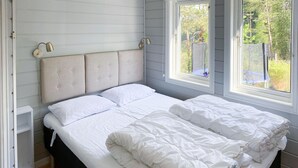A bedroom with a large bed, two bedside lamps, and a window with a view of the outdoors. - Awesome home in Hebnes with house sea view (Hebnes)