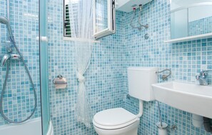A bathroom with a toilet, sink, and shower area, featuring blue mosaic tiles. - Luxurious home in Vela Luka (Vela Luka)