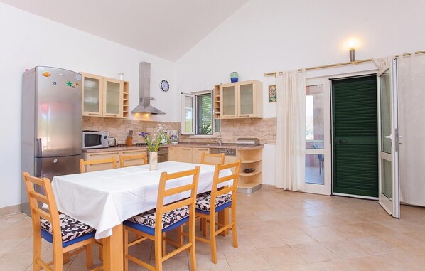 Una cocina compacta con una mesa de comedor, sillas, un refrigerador, microondas y armarios.
