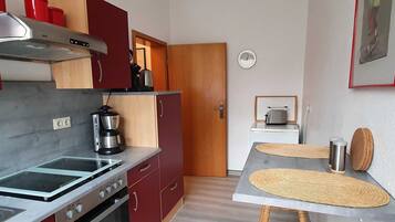 Eine kleine Küche mit Herd, Backofen, Kaffeemaschine und Toaster auf einem Tisch.