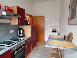 Una cocina compacta con estufa, horno, cafetera y tostadora sobre una pequeña mesa.