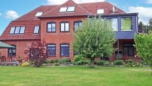 A two-story brick house with a red roof, multiple windows, and a well-maintained lawn. - Vacation apartment 2 - House Alt Ventschow (Ventschow)