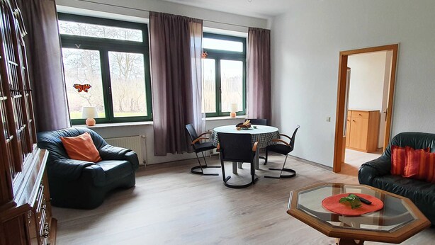 A living room with a dining table, two sofas, and a glass coffee table. - Vacation apartment 2 - House Alt Ventschow (Ventschow)