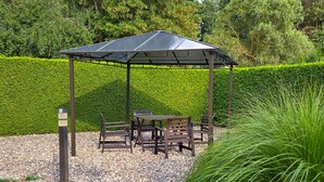 A gazebo with a table and chairs, surrounded by a gravel path and a neatly trimmed hedge. - Vacation apartment 2 - House Alt Ventschow (Ventschow)