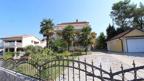 A residential building with a tiled roof, a balcony, and a paved courtyard. - Holiday apartment with shared swimming pool (Malinska)