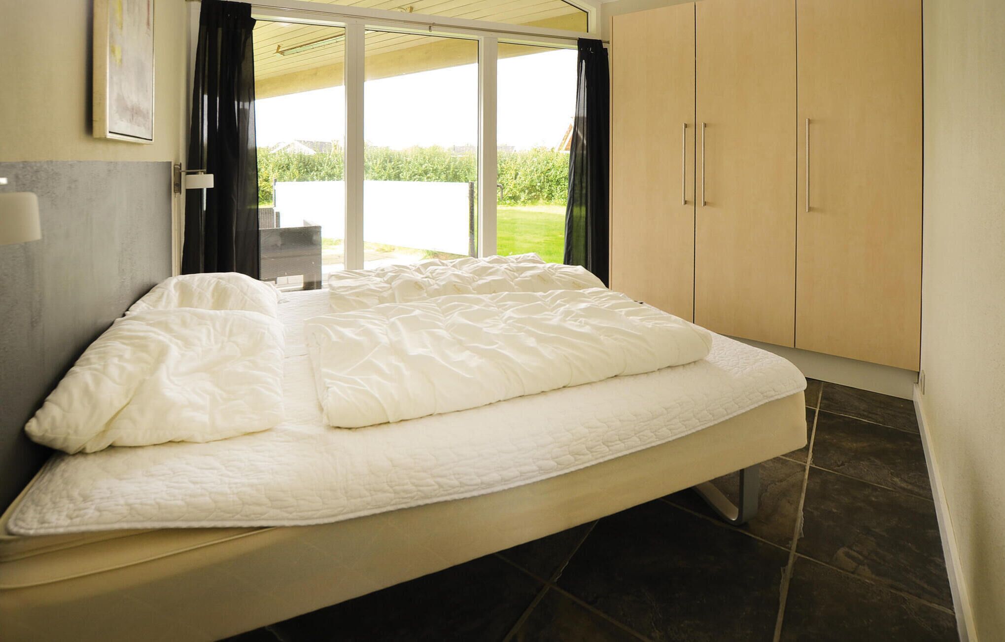 Ein Schlafzimmer mit einem Bett, einer Schiebetür zu einem Balkon und einem Kleiderschrank.