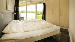 A bedroom with a bed, a sliding glass door leading to a balcony, and a wardrobe. - Beach front home in Sydals with WiFi (Sydals)