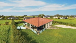A modern building with a red-tiled roof, surrounded by green fields and other houses. - Beach front home in Sydals with WiFi (Sydals)