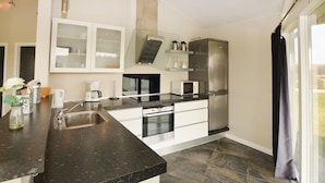 A modern kitchen with a granite countertop, stainless steel appliances, and a large refrigerator. - Beach front home in Sydals with WiFi (Sydals)
